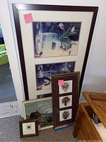 Large framed floral print leaning against wall with other art pieces around it