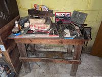 Wooden work bench with assorted hand tools displayed on top including vise on right side and tool boxes underneath
