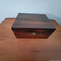 Front view of the antique rosewood box showing the brass keyhole and polished rosewood finish.