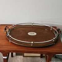 Full view of the antique oval tray showing wood base, metal handles, and surrounding metal railing with monogram plate in center.
