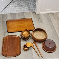 Overview of all items in the lot arranged on floor, showing trays, bowls, utensils, and cake dome.