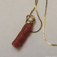 Close-up of coral pendant carved as standing figure attached to gold chain
