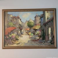 Wide view of the oil on canvas painting in its frame depicting a busy street market scene with buildings and figures.