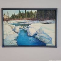 Full view of the oil painting on board depicting a snowy river scene with pine trees and mountains in the distance, in a dark blue frame.