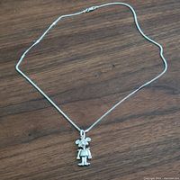 Full view of the sterling silver necklace with Mickey Mouse pendant on a wooden surface.