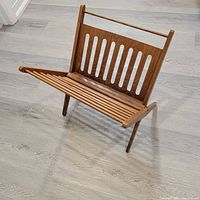 Front-side view of the wooden vintage magazine stand showing vertical slats and handle bar.