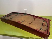 Angled view of the hockey game showing the playing surface with metal player figures and wooden frame.