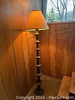 Full view of the solid brass floor lamp illuminated, showing shape, height, and lampshade.