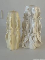 Pair of hand carved ribbon candles, cream and white, shown side by side on a white surface.