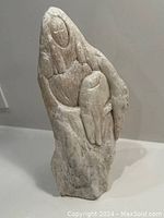 Front view of hand carved Inuit stone sculpture showing two figures, one larger holding smaller.