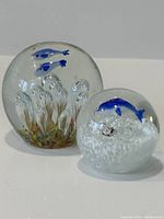 Two Mid-Century Modern glass paperweights showing detailed underwater scenes with fish and bubbles