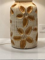 Close-up of ceramic lamp base showing recessed daisy patterns and glossy glaze finish