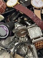 Photo showing a mix of watches with leather and metal straps, round and square faces, including a Fossil watch with rhinestones and a Timex digital watch.