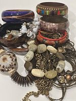 Photo shows a variety of vintage bracelets and necklaces piled together displaying stone, shell, wood, and metal components in natural earthy colors and textures.