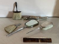Overall view on quilted white surface showing mirror, comb, silver and wooden brushes