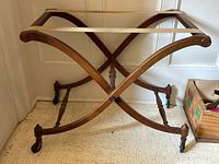 Full front view of walnut folding rack with canvas strap top and caster wheels