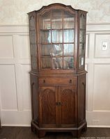 Front view of full antique oak display cabinet with glass paneled upper doors and wooden lower doors with drawer