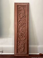 Full front view of entire carved wood panel leaning against wall
