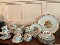 Full overview of cups and saucers arranged in groups across tabletop beneath serving pieces