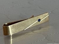 Front and side view showing diagonal groove and bezel-set blue sapphire
