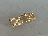 Front view of both cufflink faces showing engine-turned geometric texture and stud accents