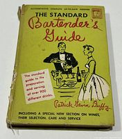 Front cover of the yellow hardcover book displaying the title, author, and thematic graphics related to bartending and drinks.