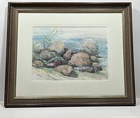Frontal view of framed Lillian Hagter watercolour painting "Quiet Cove" showing the scene of rocks by water with grasses, in brown frame with white mat.