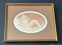 Framed oval-shaped etching of a nude woman reclining, detailed view of frame and overall presentation.