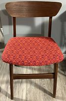 Front view of the chair showing the curved teak wood backrest and vibrant upholstered seat with geometric pattern.