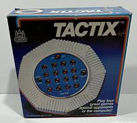 Box showing Tactix game branding, image of the game unit, and marketing text indicating 4 games playable against opponents or computer.