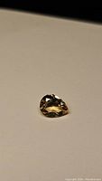 Pear shaped natural golden citrine gemstone on white background showing facets and color.