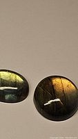 Two oval labradorite cabochons showing multicolored flashes on a plain background
