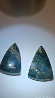 Pair of triangular natural moss agate cabochons with visible unique moss-like inclusions and polished surfaces.