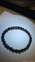 Photo of the natural red tiger eye stretchy bracelet with polished round beads on a stretchy cord shown in a circular shape.
