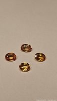 Four oval-cut natural Fanta orange sapphires arranged on a white background, showing the color and cut in natural light.
