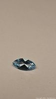 Close-up photo of the natural sky blue topaz marquis cut gemstone lying on a plain surface.