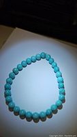 Photo of the turquoise beaded stretchy bracelet laid flat showing the round beads and elastic string.
