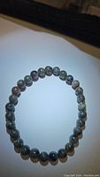 Natural yooperlite stretchy bracelet laid flat showing round beads and natural patterns under bright light.