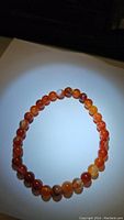 Photo of a round stretchy bracelet made from polished natural red agate beads showing color and banding patterns.