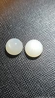 Two round natural white moonstone cabochons with visible moonstone flash, shown on textured black surface.
