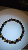 Photo of natural tigerseye and black bead stretchy bracelet laid flat showing bead details.