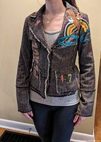 Front view of brown tweed blazer featuring embroidered rainbow, bird, clouds, and patches with frayed edges