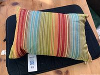 Front view of multicolor striped throw pillow on wooden table