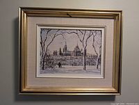 Framed print showing Parliament Building with snow and bare winter trees, gold frame with fabric matting.