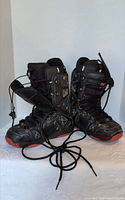 Pair of black DC ladies snowboard boots size US 7.5 shown from front angle with visible red soles and lace-up details.