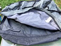 Open view of the interior of the soft roof top carrier showing water-resistant lining and buckles on outer fabric edges.