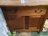 Front view of wooden wash stand showing drawer and two-door cabinet below.