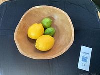 Top view of wooden fruit bowl showing interior and lemons and limes inside for scale