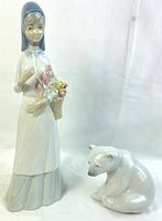 Photo showing both figurines together: a standing girl with a basket of flowers and a seated polar bear, on a plain white background.