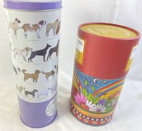 Two cylindrical tubes containing sealed 1000-piece puzzles, one lavender with dog breed illustrations and one red with colorful floral graphics.
